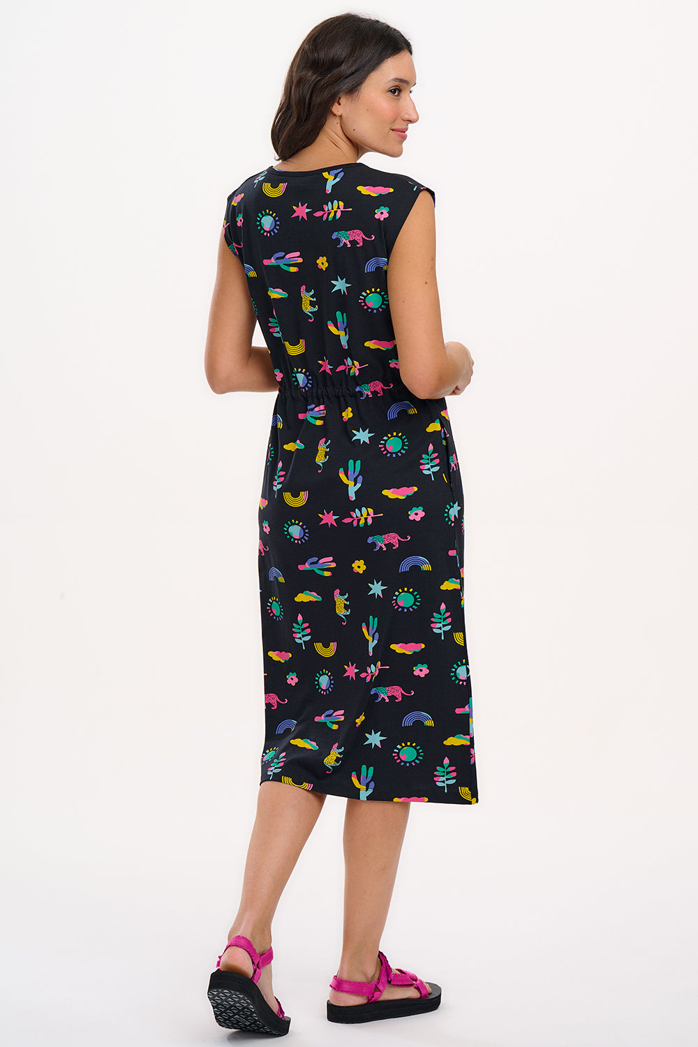 A model wearing a black midi dress with a colorful animal and floral print, standing against a white background.