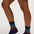 A person's legs wearing navy blue crew socks with a colorful geometric pattern near the cuffs, paired with a denim skirt against a plain light background.