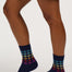 A person's legs wearing navy blue crew socks with a colorful geometric pattern near the cuffs, paired with a denim skirt against a plain light background.