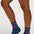 A person wearing dark blue crew socks with pink and purple striped cuffs and a pink tiger graphic, paired with a blue denim skirt against a light gray studio background.