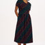 A model wearing a midi-length jersey cotton dress with a round neckline, elasticated waistband, short sleeves, and a pattern of undulating waves in black, red, and green.