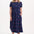Woman wearing a navy dress with colorful polka dots on a white background
