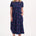 Woman wearing a navy dress with colorful polka dots on a white background