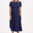 Woman wearing a navy dress with colorful polka dots on a white background
