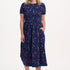 Woman wearing a navy dress with colorful polka dots on a white background