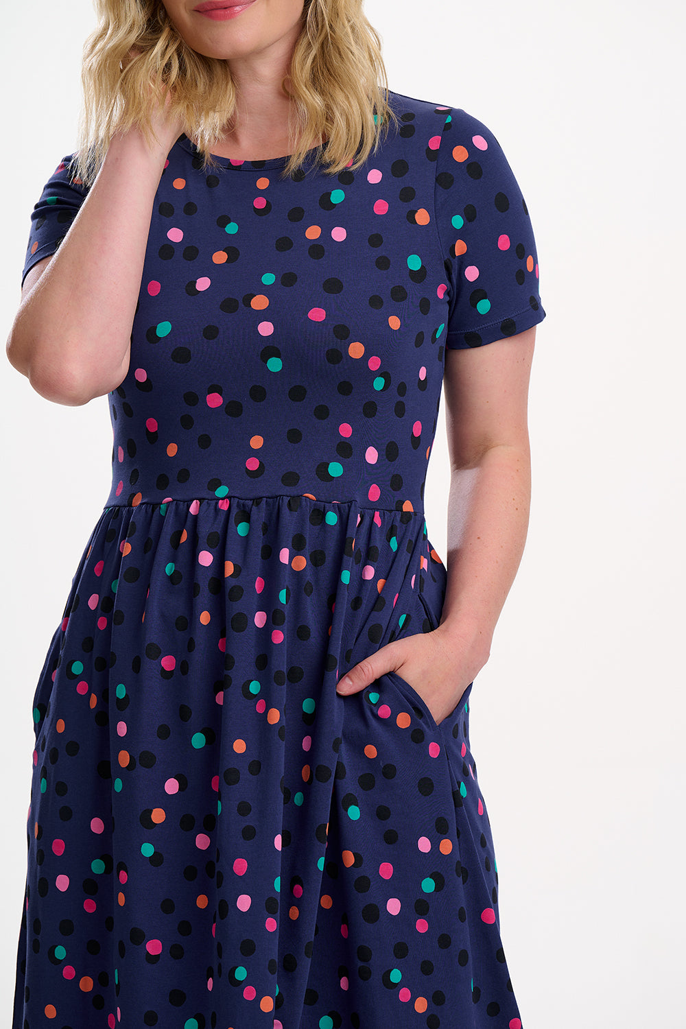 Navy dress with colorful polka dots worn by a person on a white background