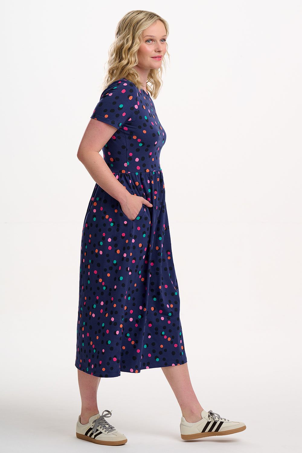 Woman wearing a navy dress with colorful polka dots on a white background
