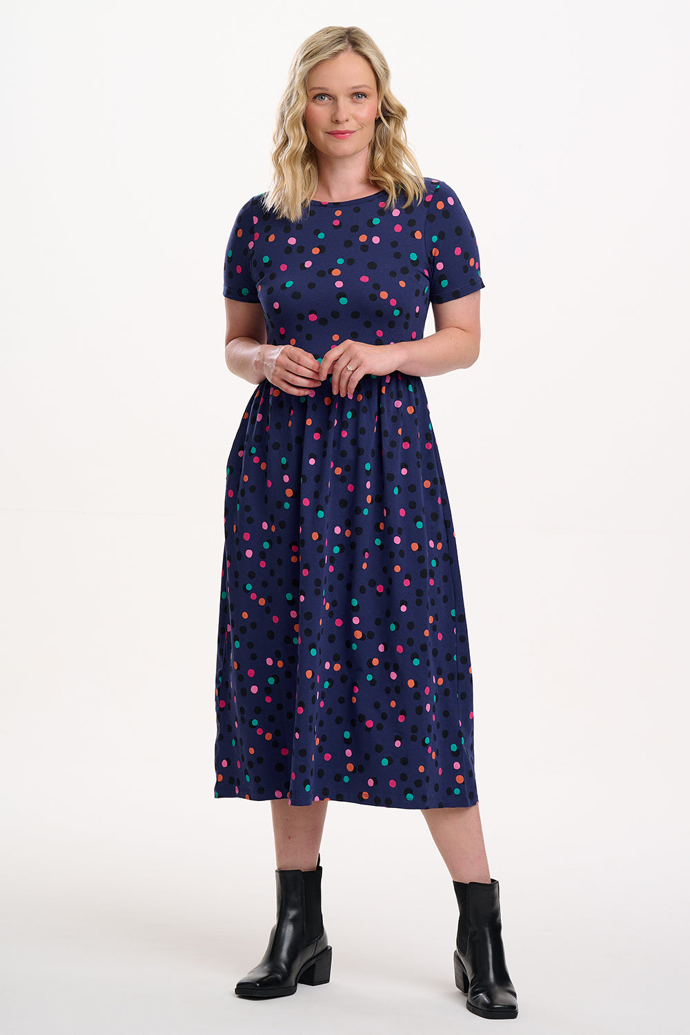 Woman wearing a navy dress with colorful polka dots on a white background