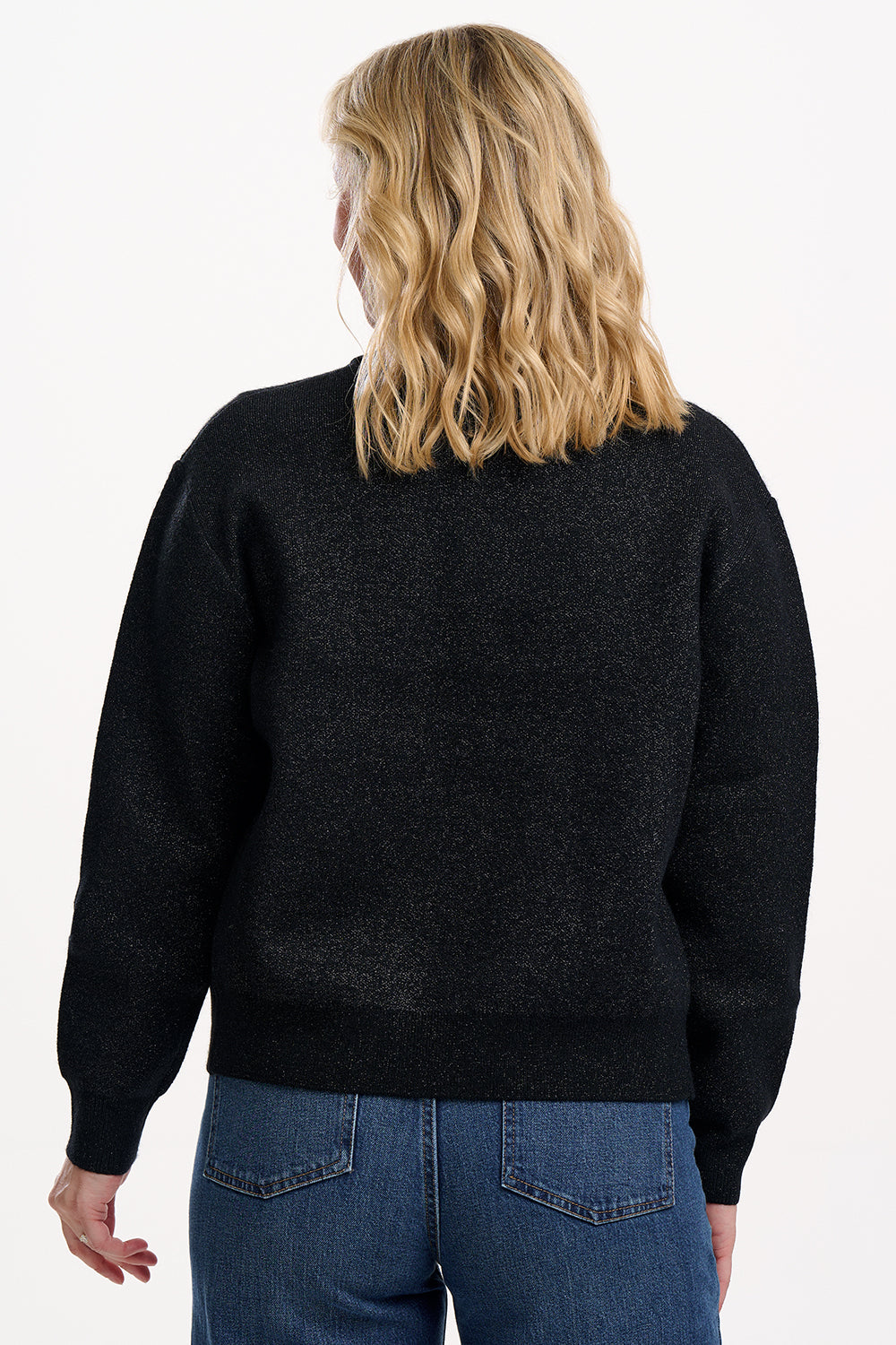 Person wearing a black sweater and blue jeans on a white background