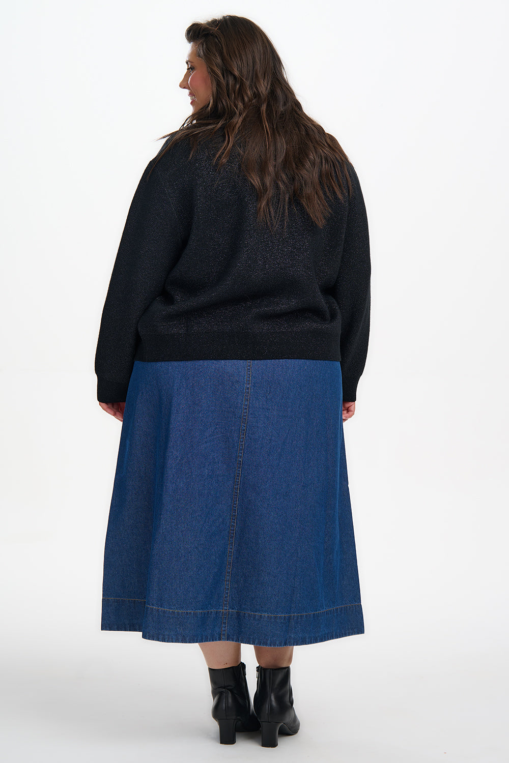 Person wearing a black sweater and blue skirt on a white background