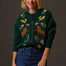 Woman wearing a green sweater with horse and floral patterns against a dark background
