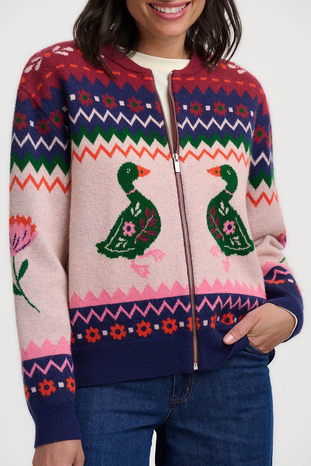 Person wearing a colorful sweater with duck designs on a white background