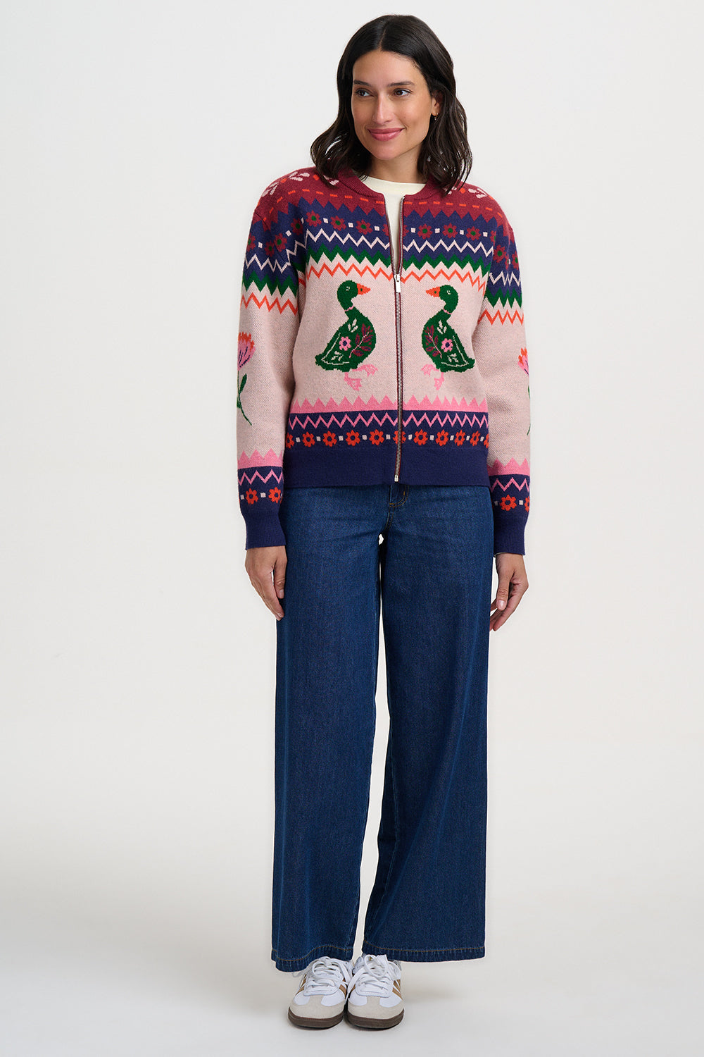 Woman wearing a colorful patterned sweater with duck designs on a white background