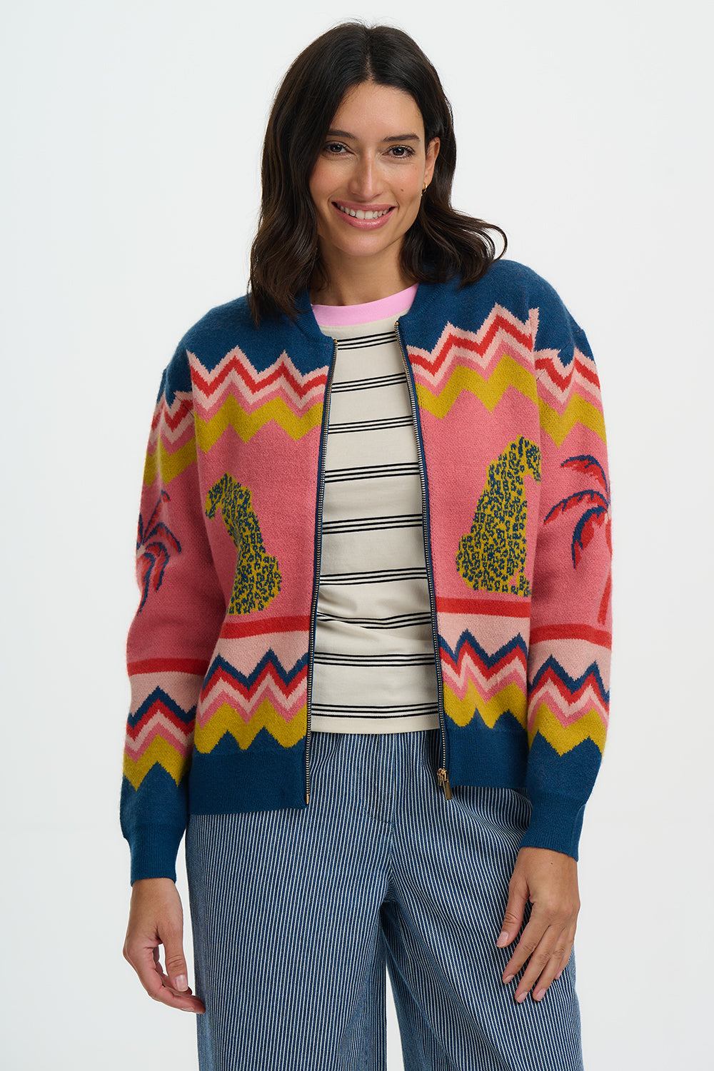 Woman wearing a colorful patterned cardigan over a striped shirt with a white background