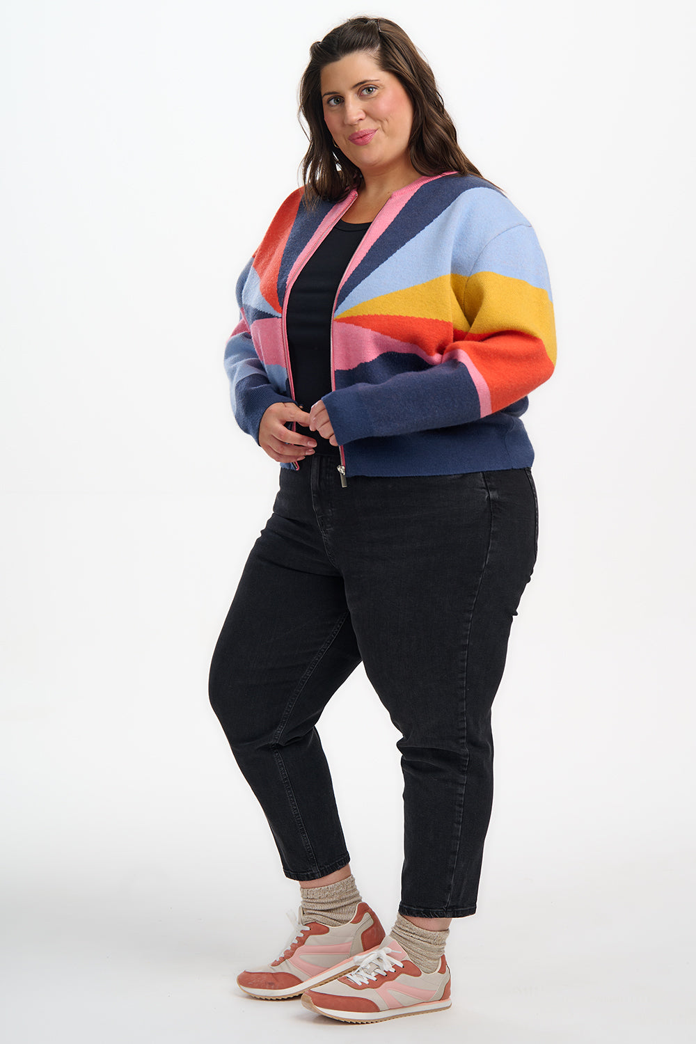 Person wearing a colorful striped sweater and black pants on a white background