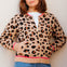 Woman wearing a leopard print cardigan with pink trim against a light background