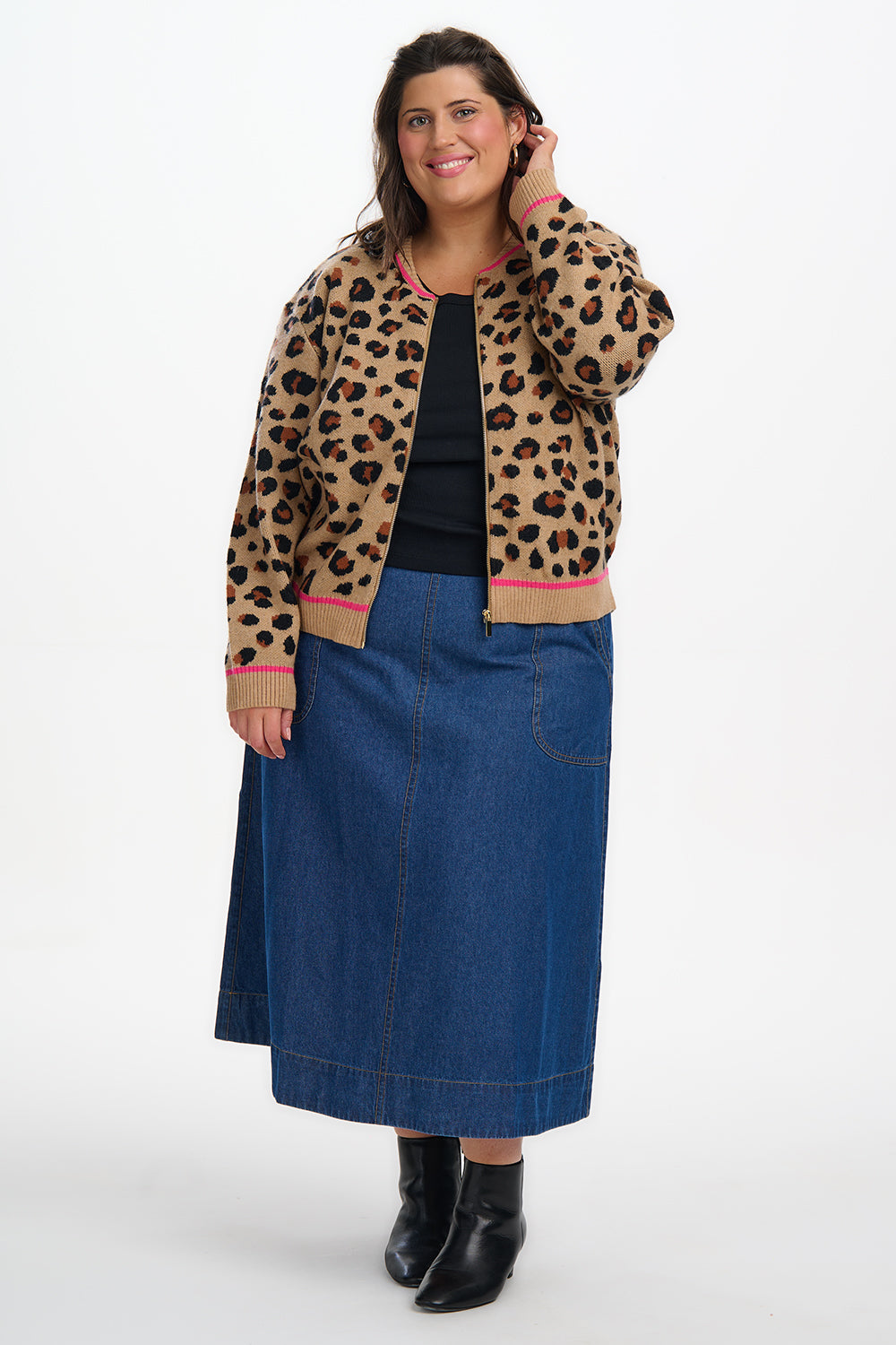 Woman wearing a leopard print jacket, black top, and blue denim skirt on a white background
