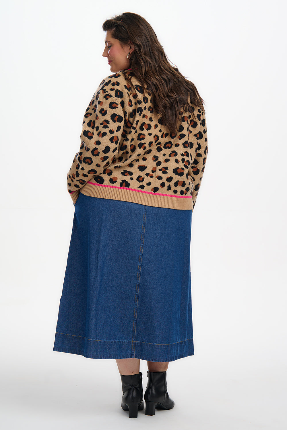 Person wearing a leopard print sweater and blue skirt on a white background