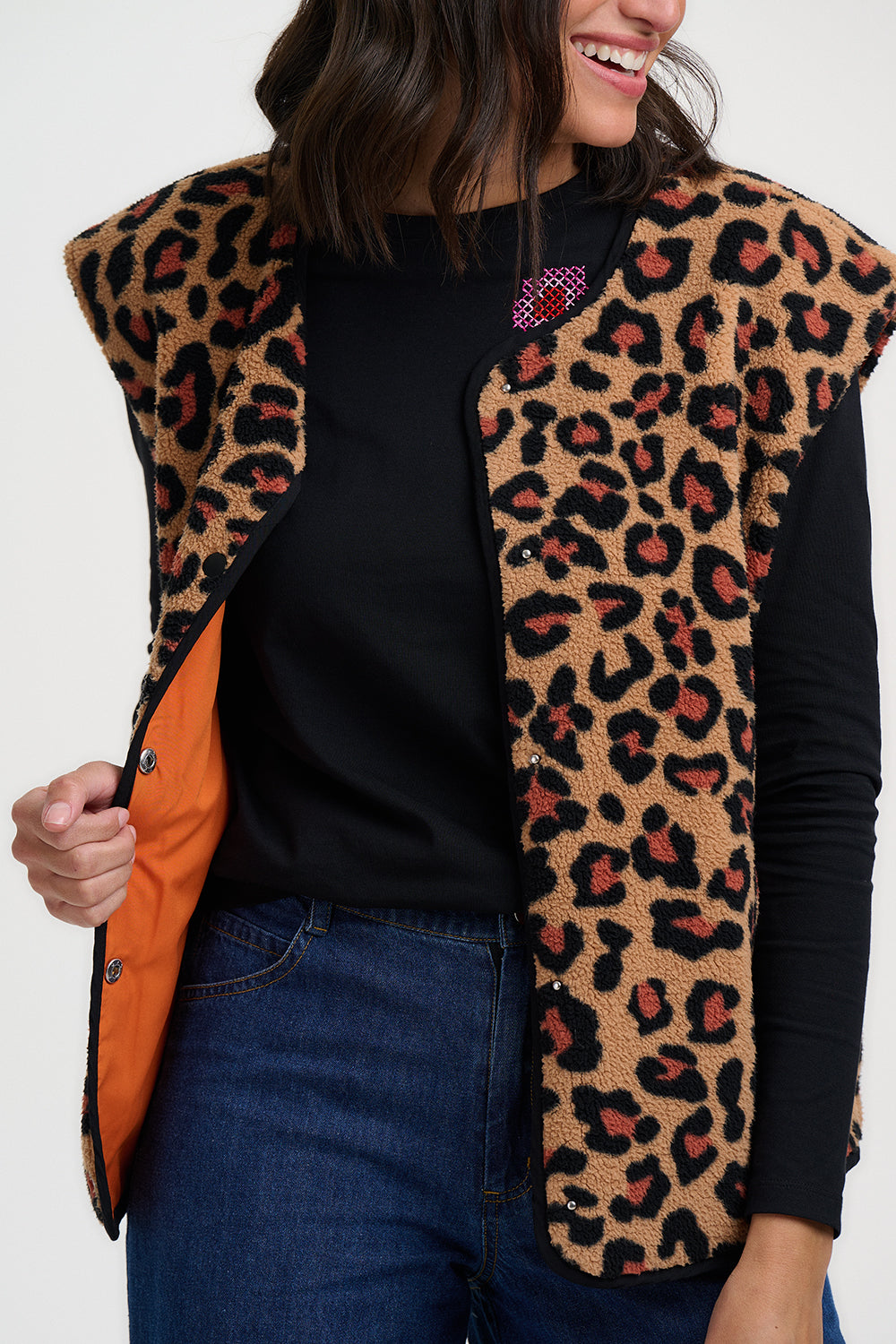 Person wearing a leopard print vest over a black shirt with an orange interior.
