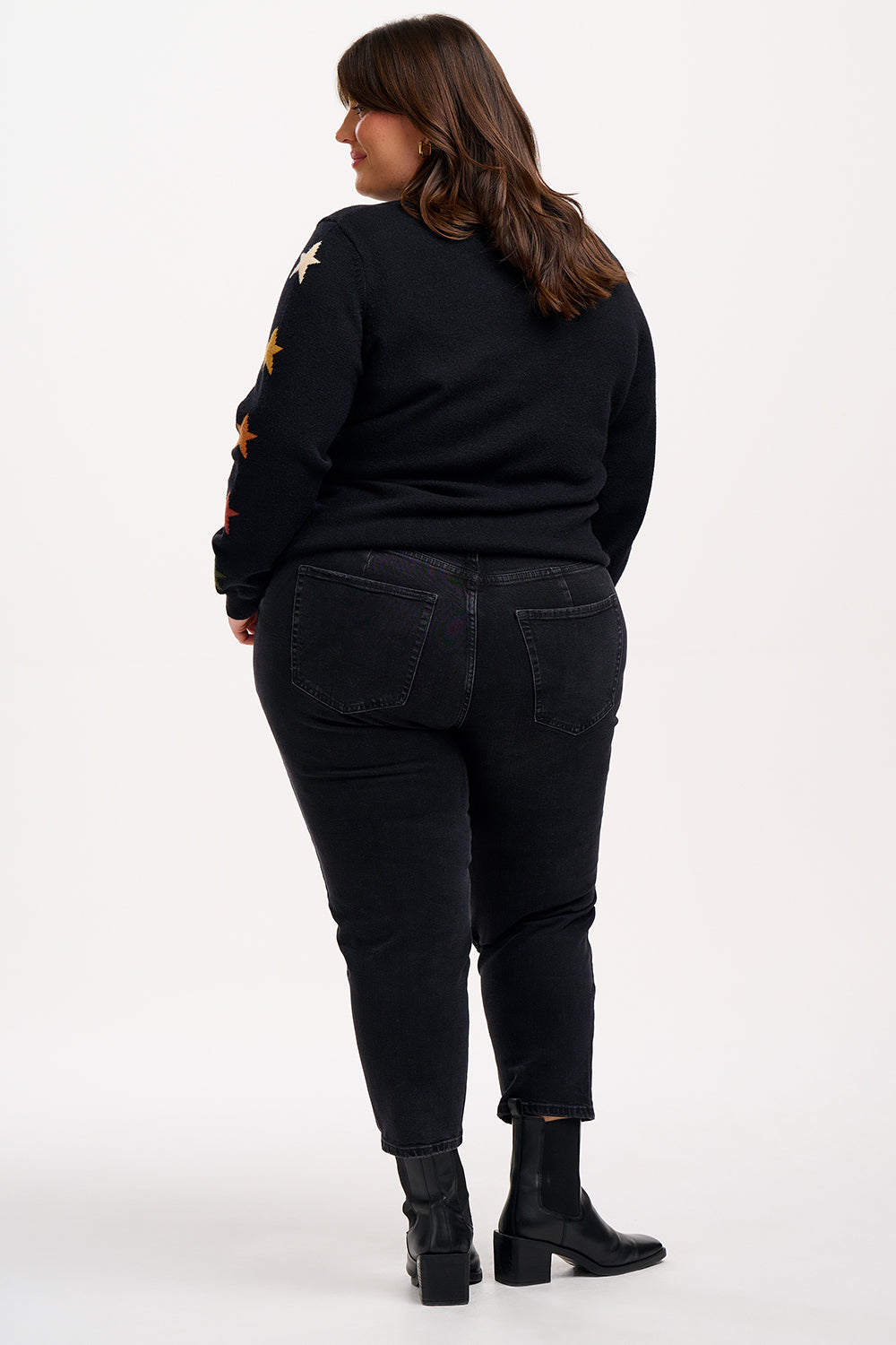 model wearing a black jumper with stars on the sleeves 