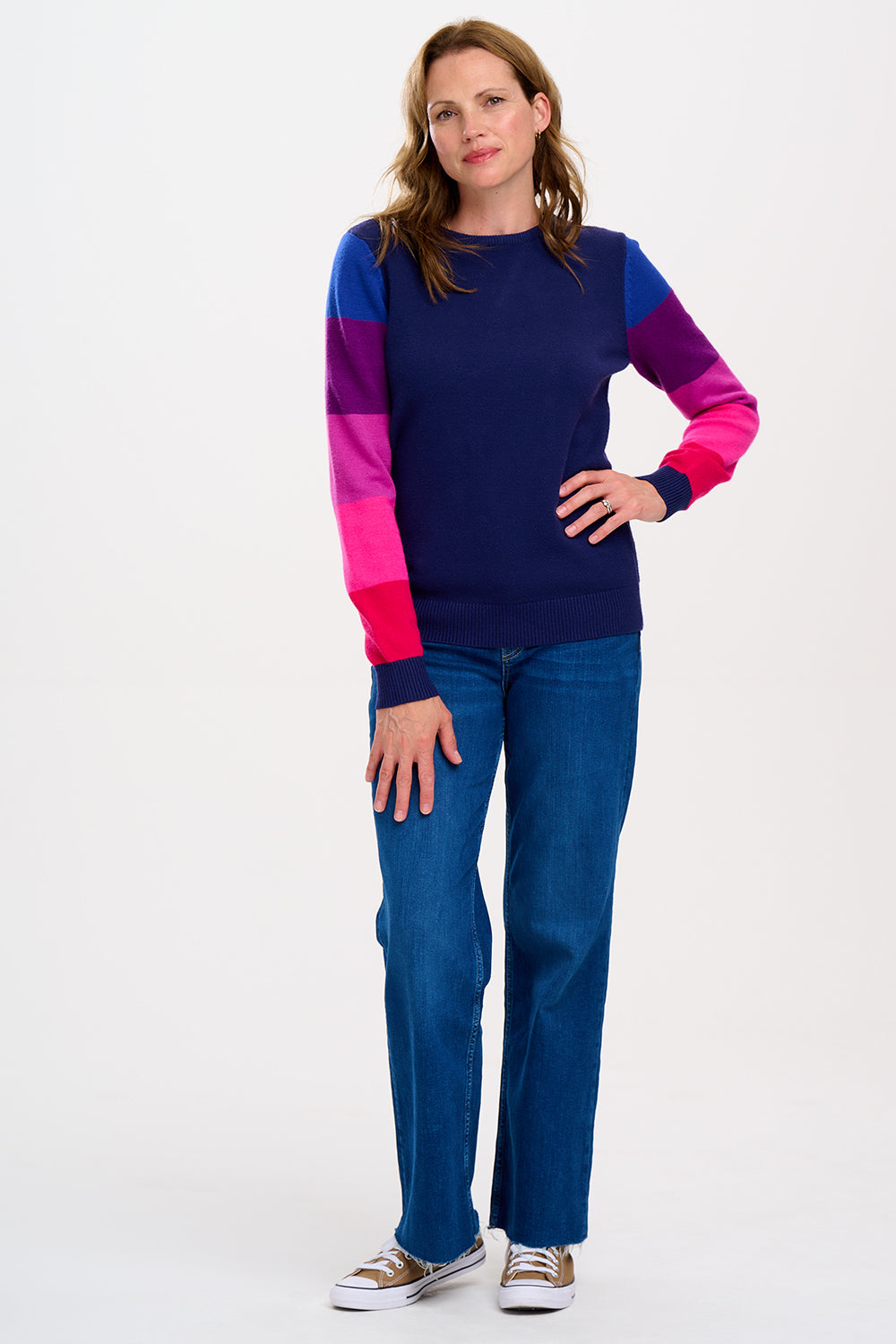 A model wearing a navy crew neck jumper with colour block sleeves in pink and purple. 