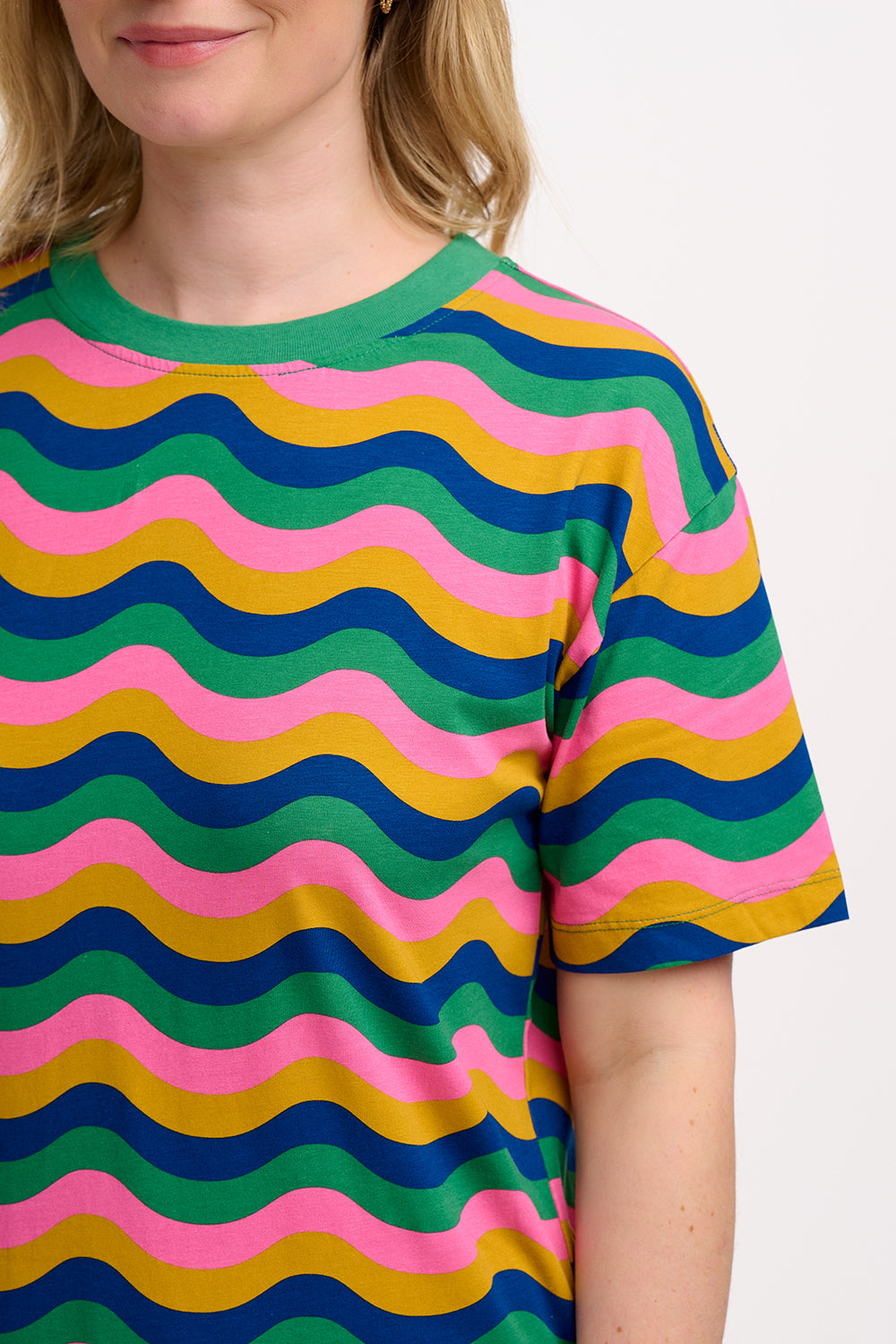 A model wearing a midi t-shirt dress with a multicolor rainbow waves print. The dress is knee-length, has a ribbed collar, and short sleeves.