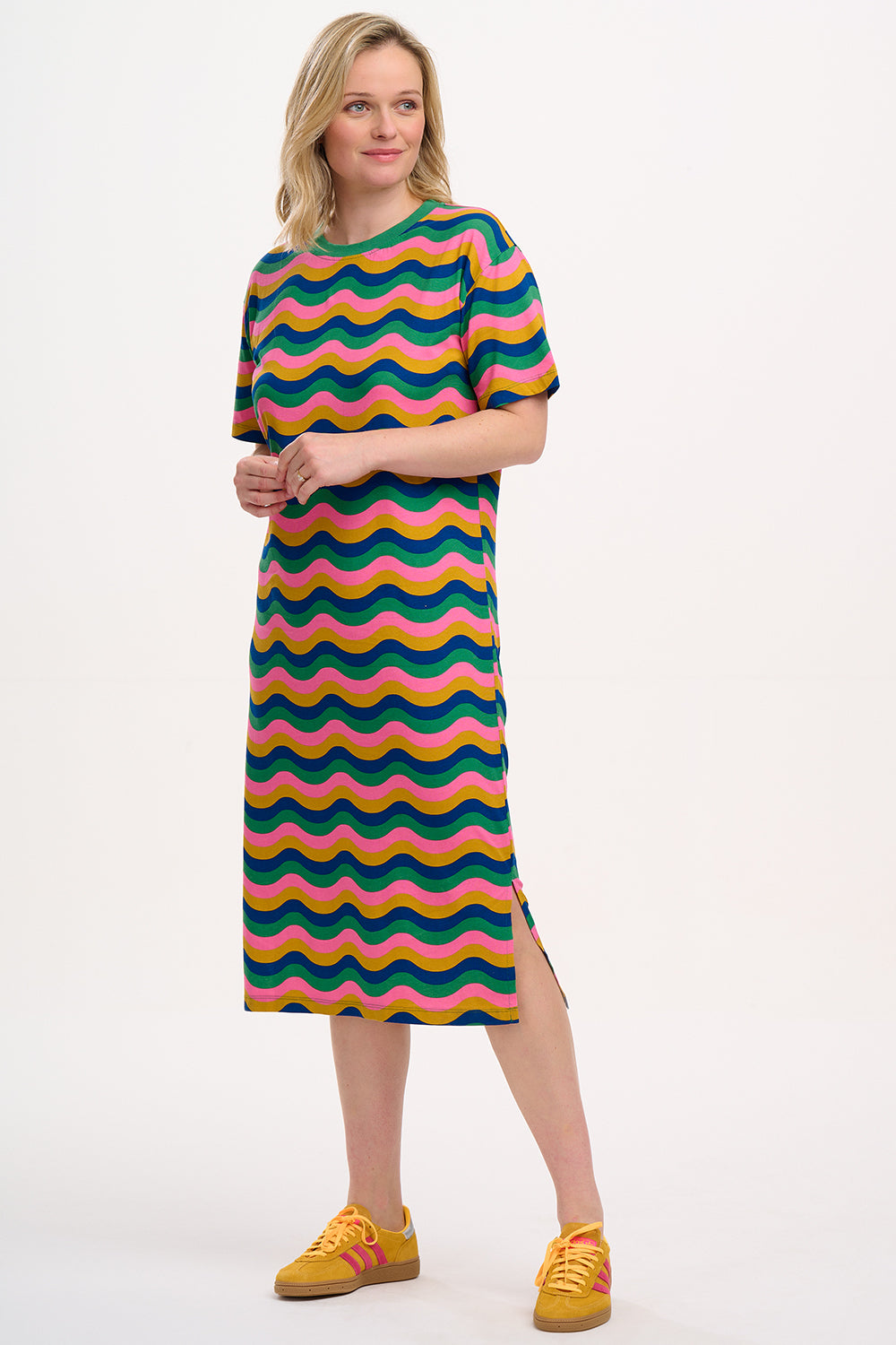 A model wearing a midi t-shirt dress with a multicolored geometric pattern in shades of pink, green, blue, and tan.