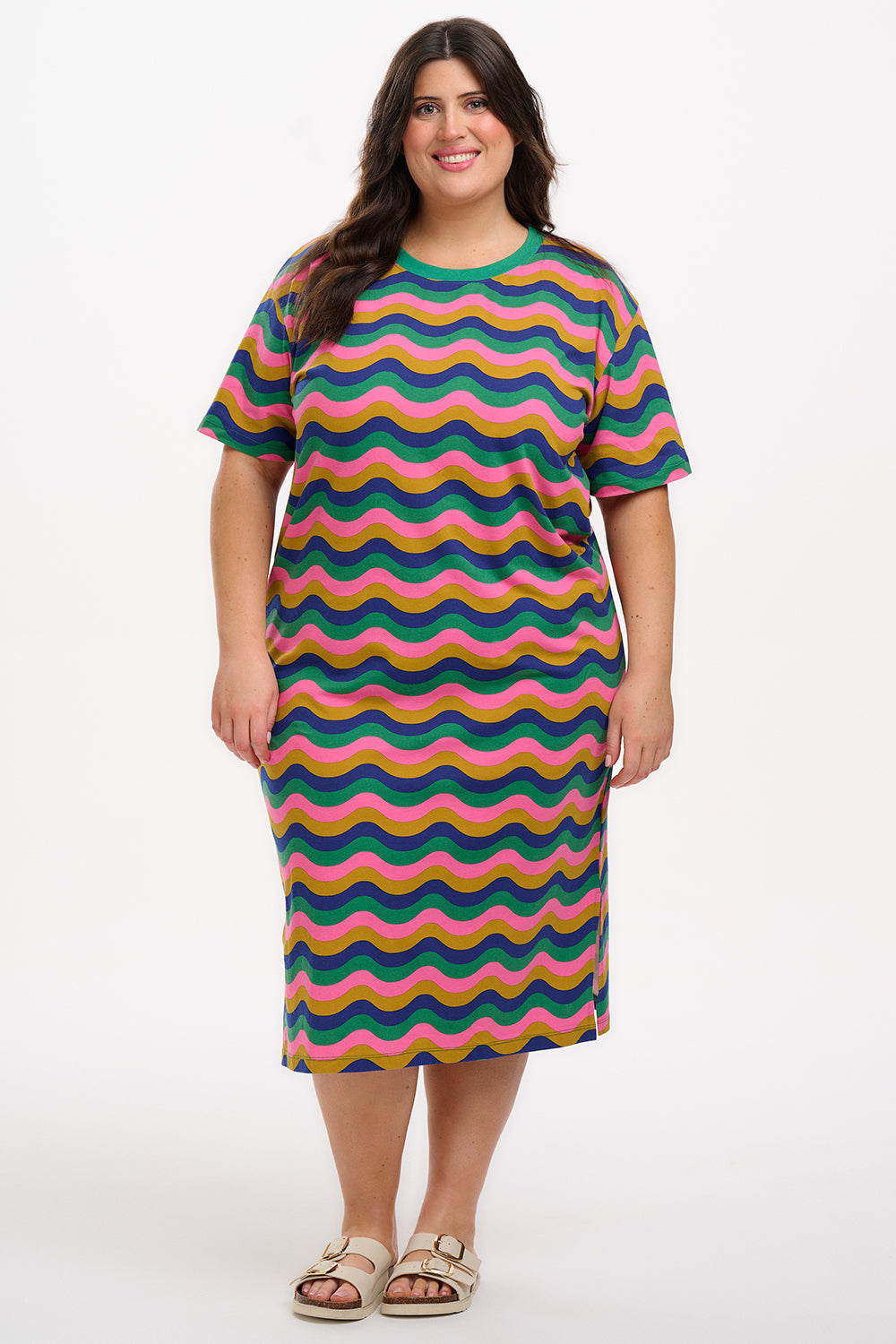 A model wearing a midi t-shirt dress with a multicolor rainbow waves print. The dress is knee-length, has a ribbed collar, and short sleeves.