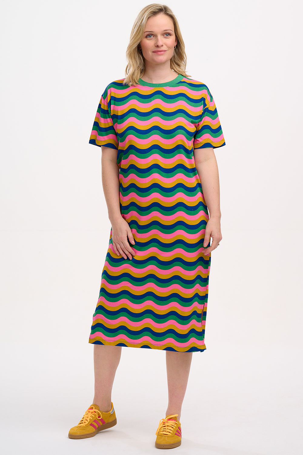 A model wearing a midi t-shirt dress with a multicolor rainbow waves print. The dress is knee-length, has a ribbed collar, and short sleeves.
