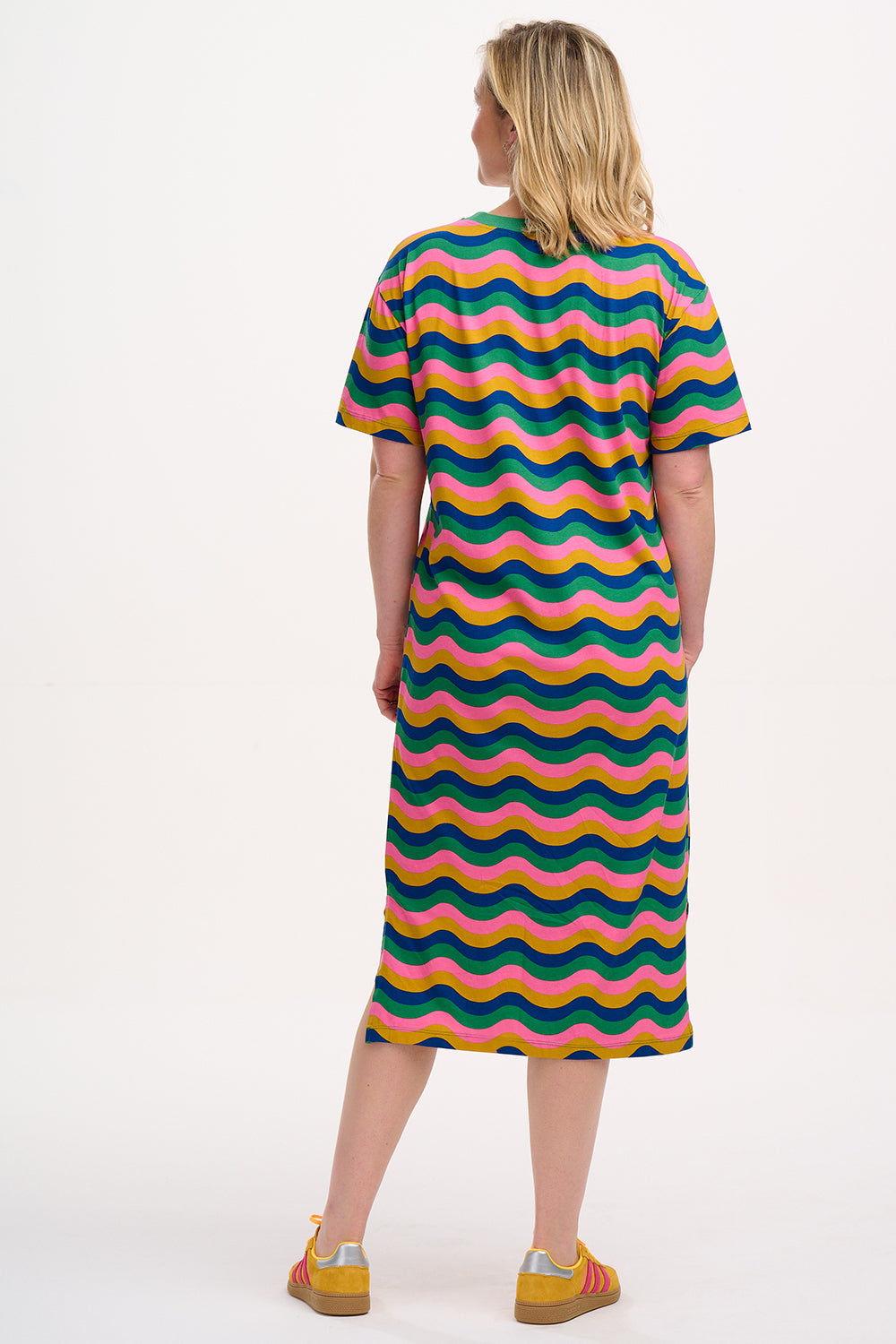 A model wearing a midi t-shirt dress with a multicolor rainbow waves print. The dress is knee-length, has a ribbed collar, and short sleeves.
