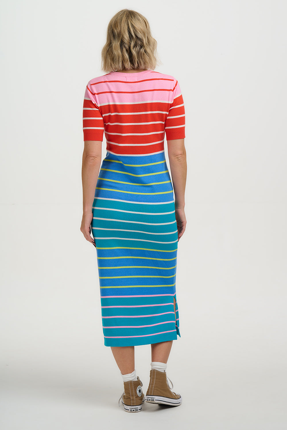 Person wearing a red and white striped top with a blue and yellow striped skirt on a white background