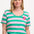 A woman wearing a green and pink striped scoop neck t-shirt with a flower detail on the chest.