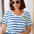 Woman wearing a blue and white striped shirt with sunglasses indoors.