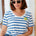 Woman wearing a blue and white striped shirt with sunglasses indoors.