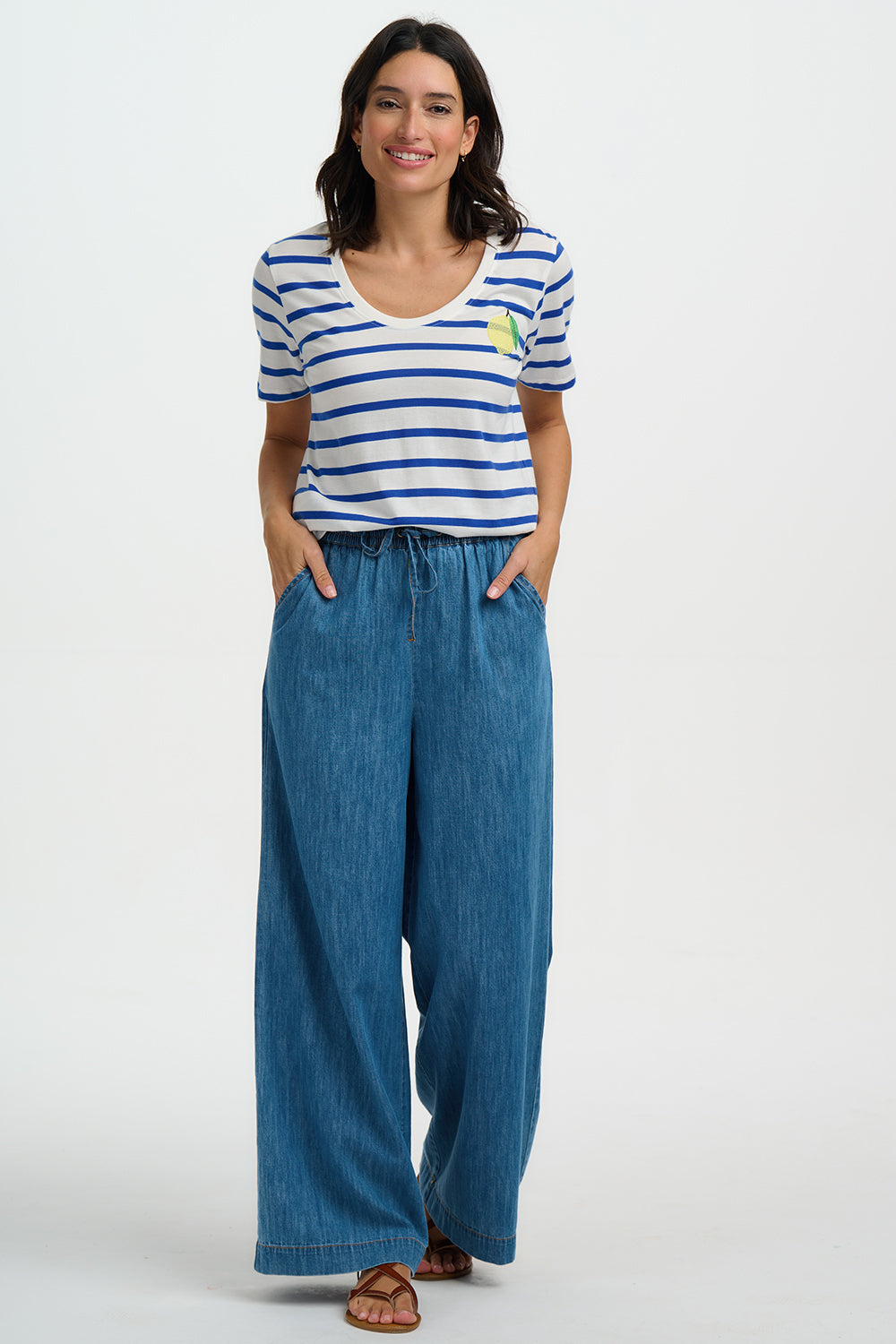 Woman wearing a striped shirt and wide-leg jeans on a white background