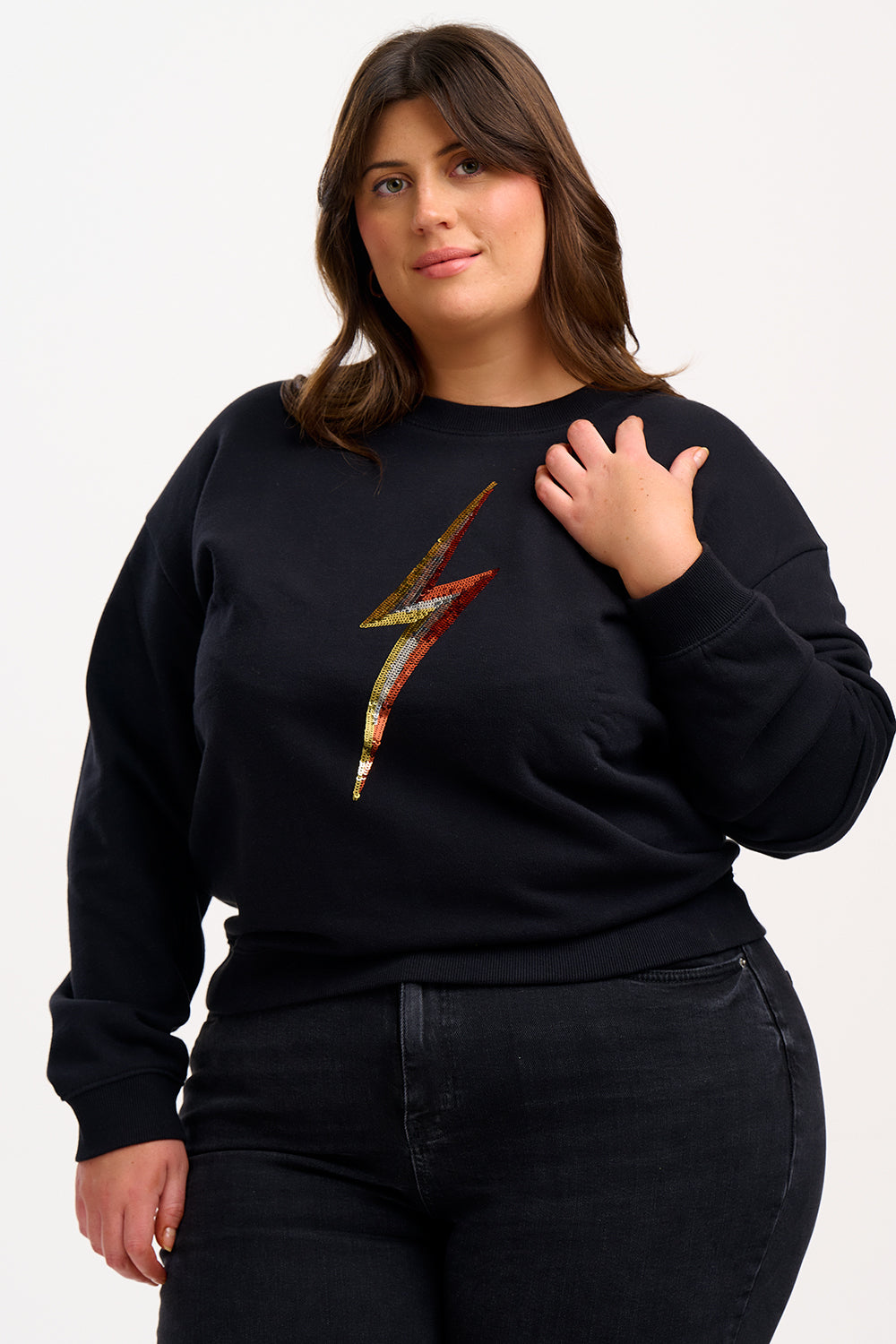 A person wearing a black sweatshirt with a sequin lightning bolt design on the front