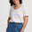 Woman wearing a colorful striped shirt and blue pants against a white background