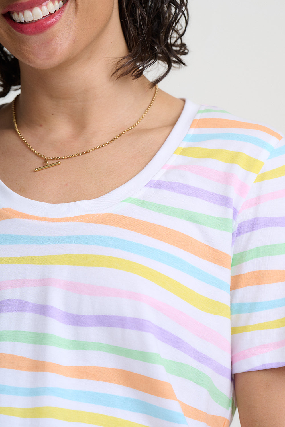 Person wearing a colorful striped shirt with a gold necklace.