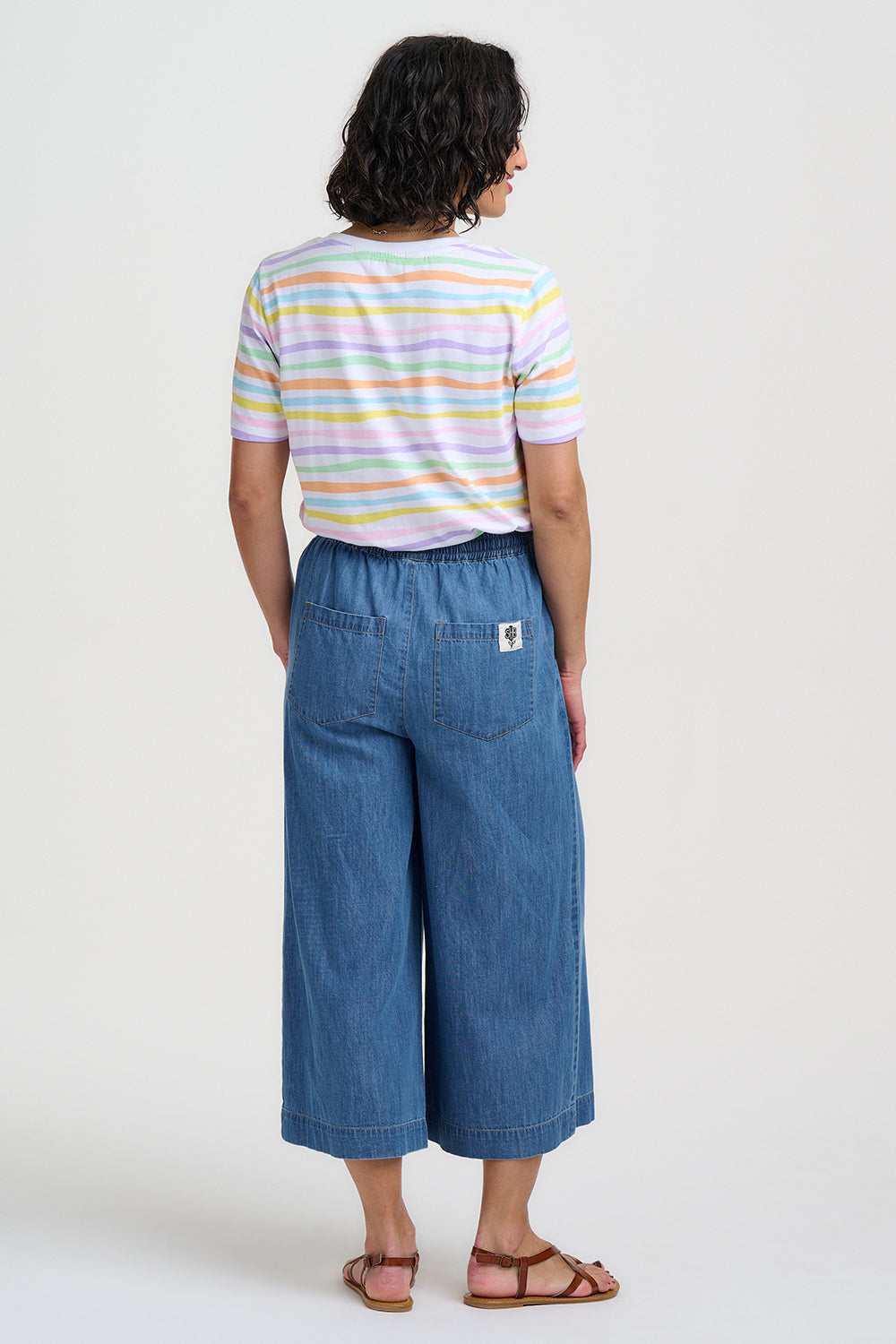 Person wearing a striped shirt and blue denim pants on a white background