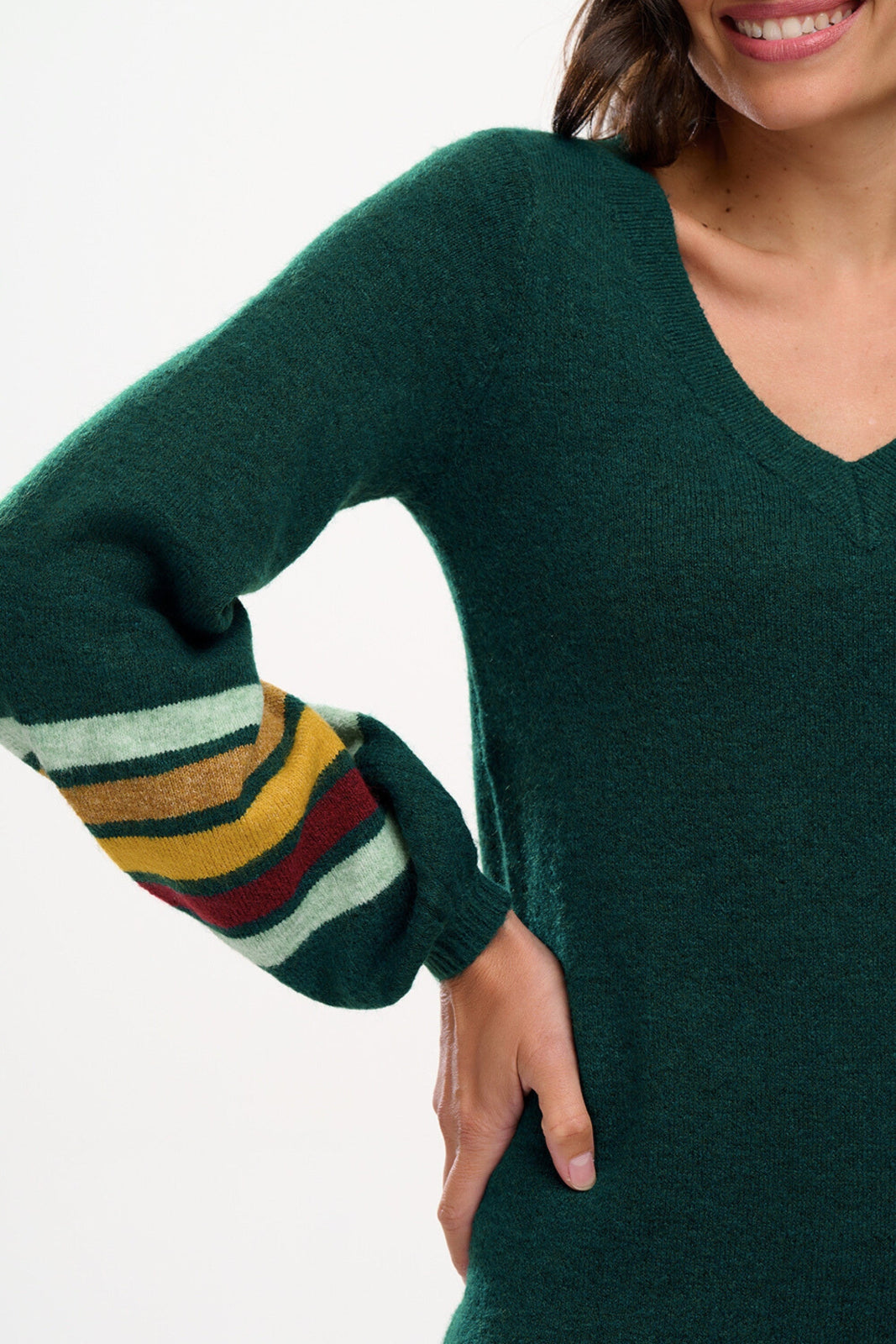 Green sweater with multicolored sleeves worn by a person on a white background
