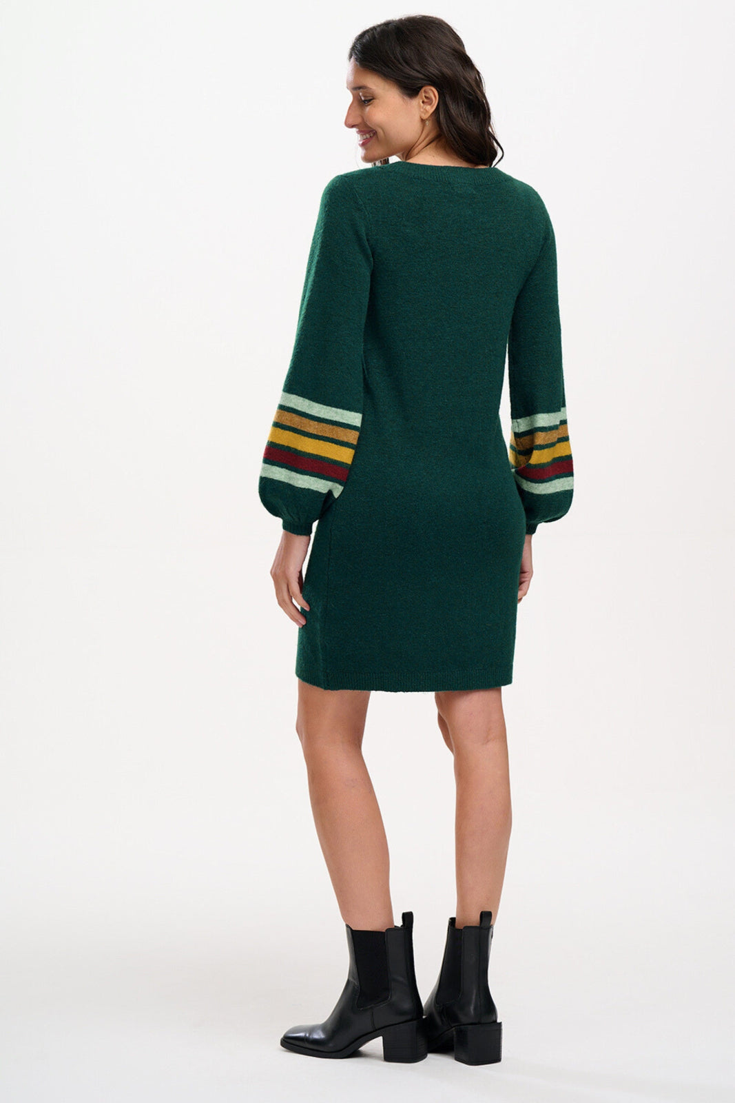Woman wearing a green sweater dress with colorful stripes on sleeves against a white background