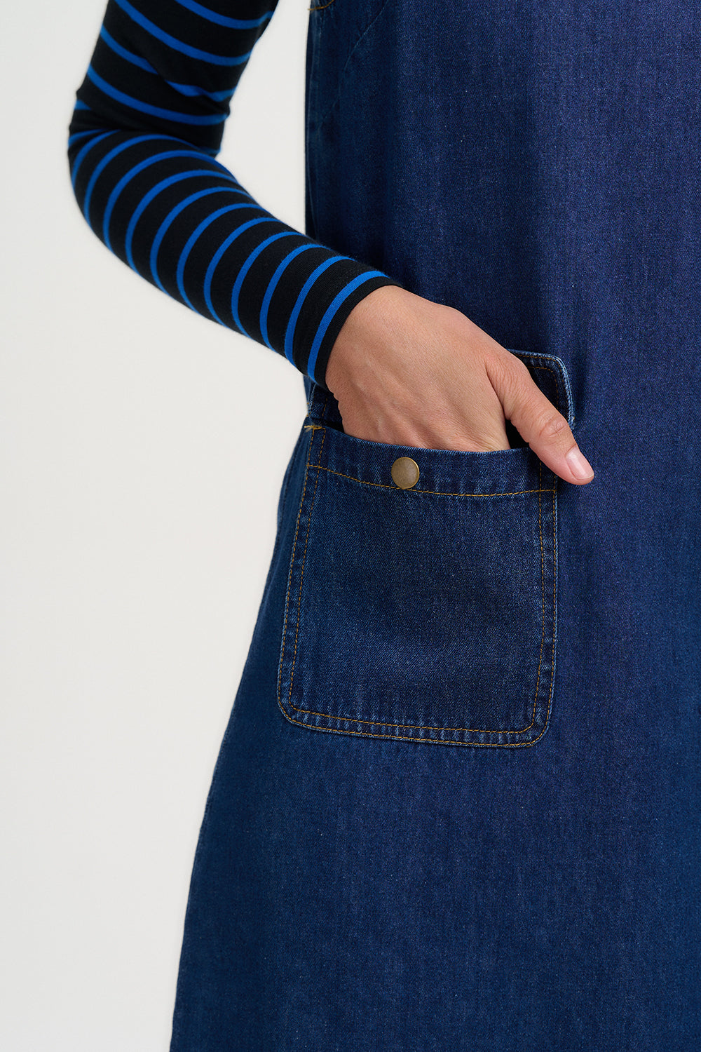 Person wearing a blue denim apron with a white background