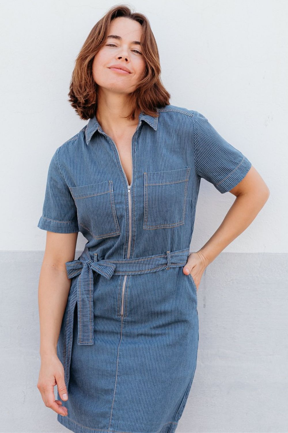 Woman wearing a blue denim dress against a light background