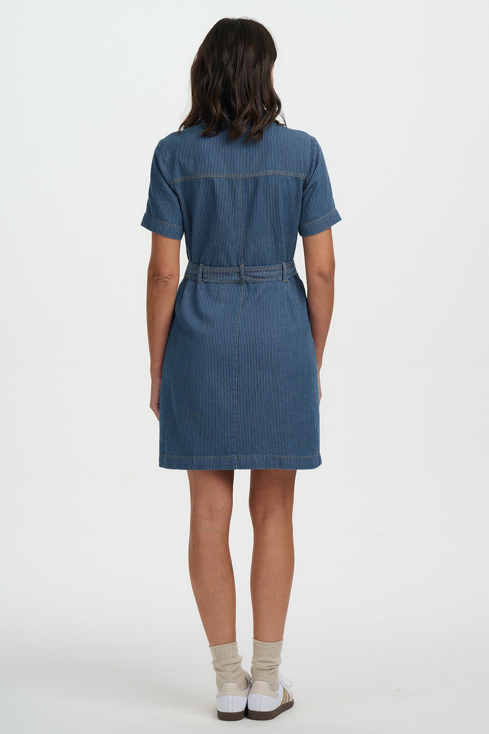 Person wearing a blue denim dress on a white background