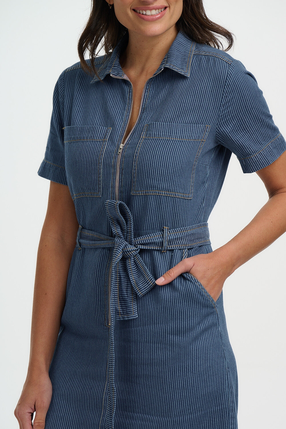 Woman wearing a blue denim dress with a white background