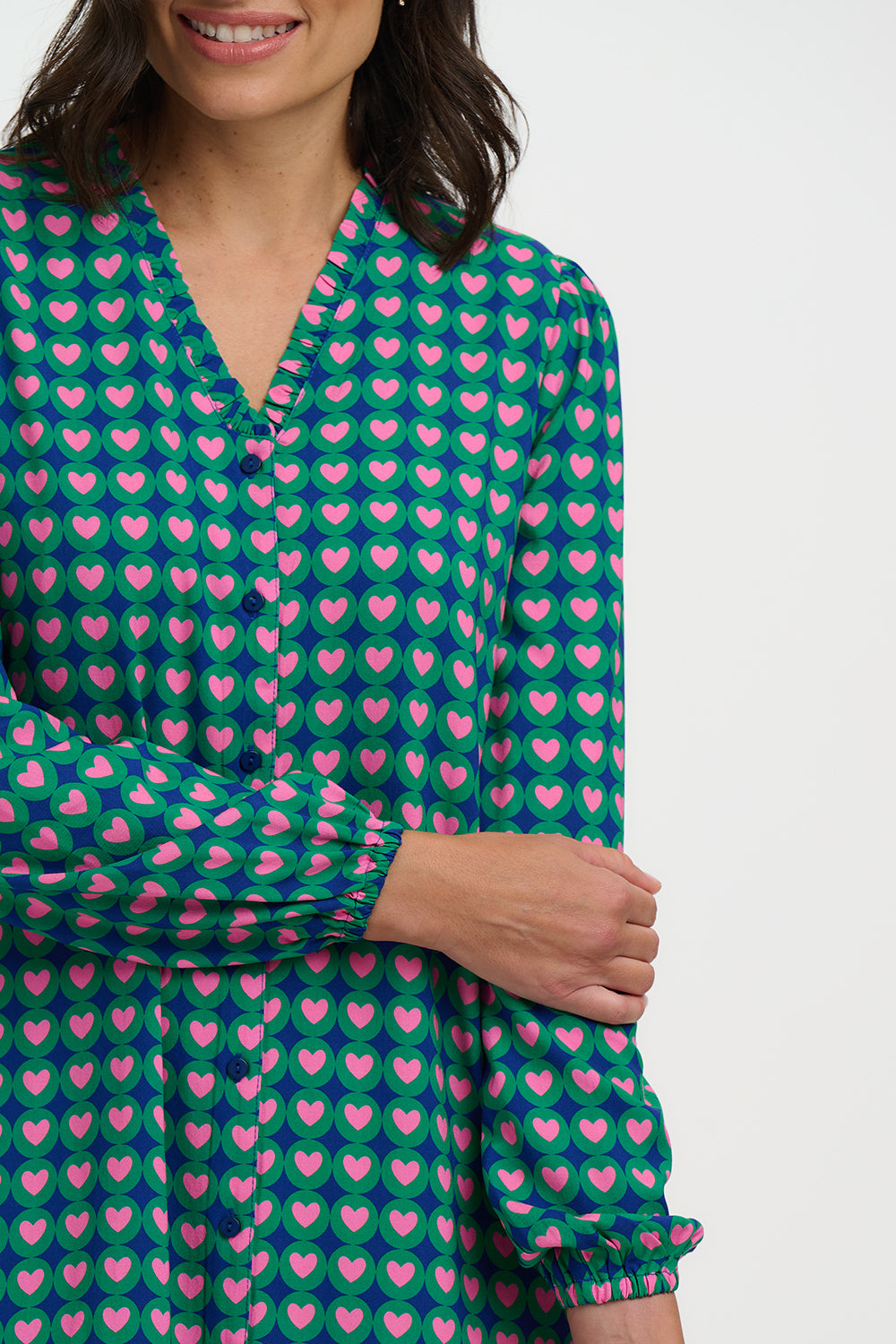 Woman wearing a green dress with pink heart pattern on a white background