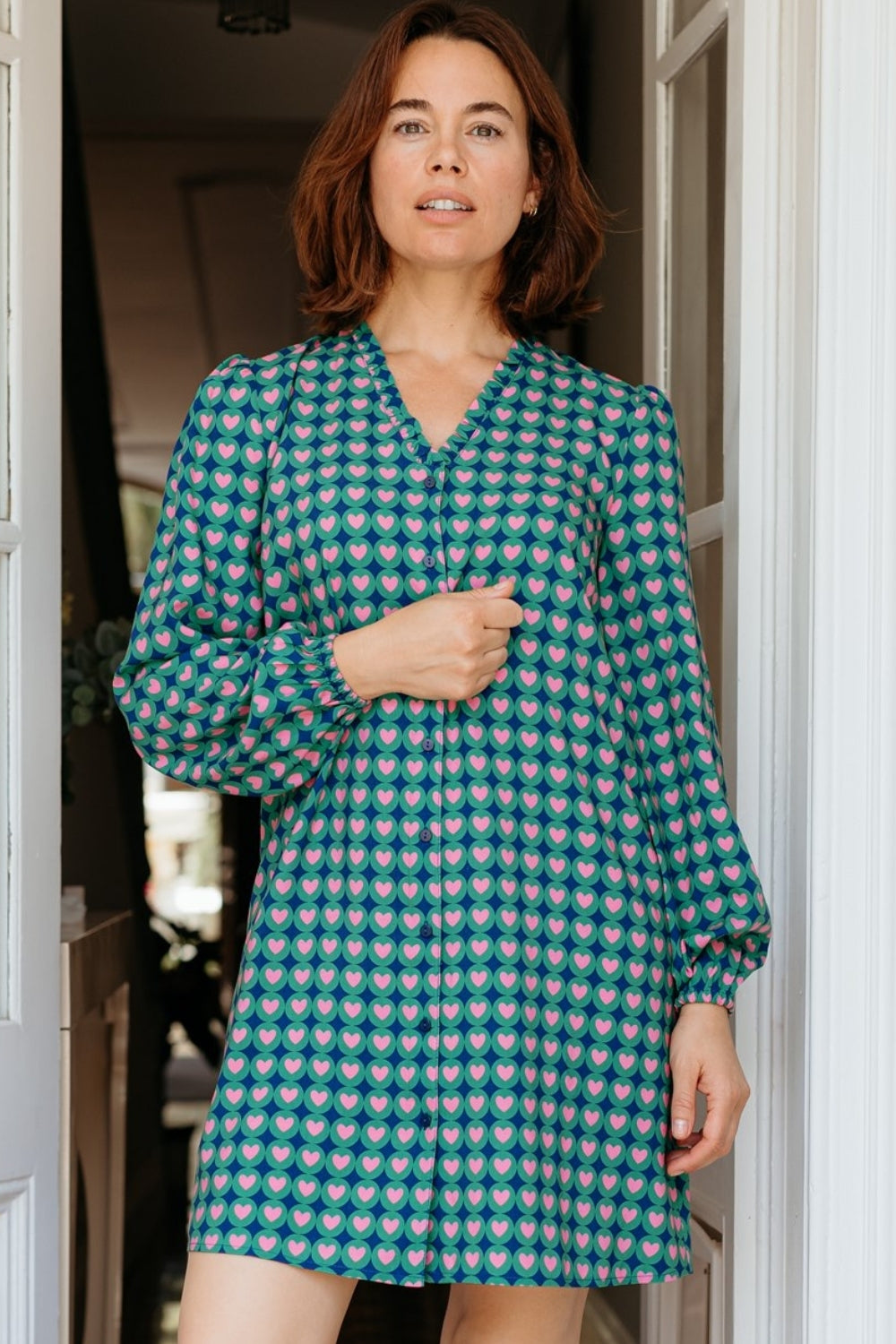 Woman wearing a patterned dress standing in a doorway.