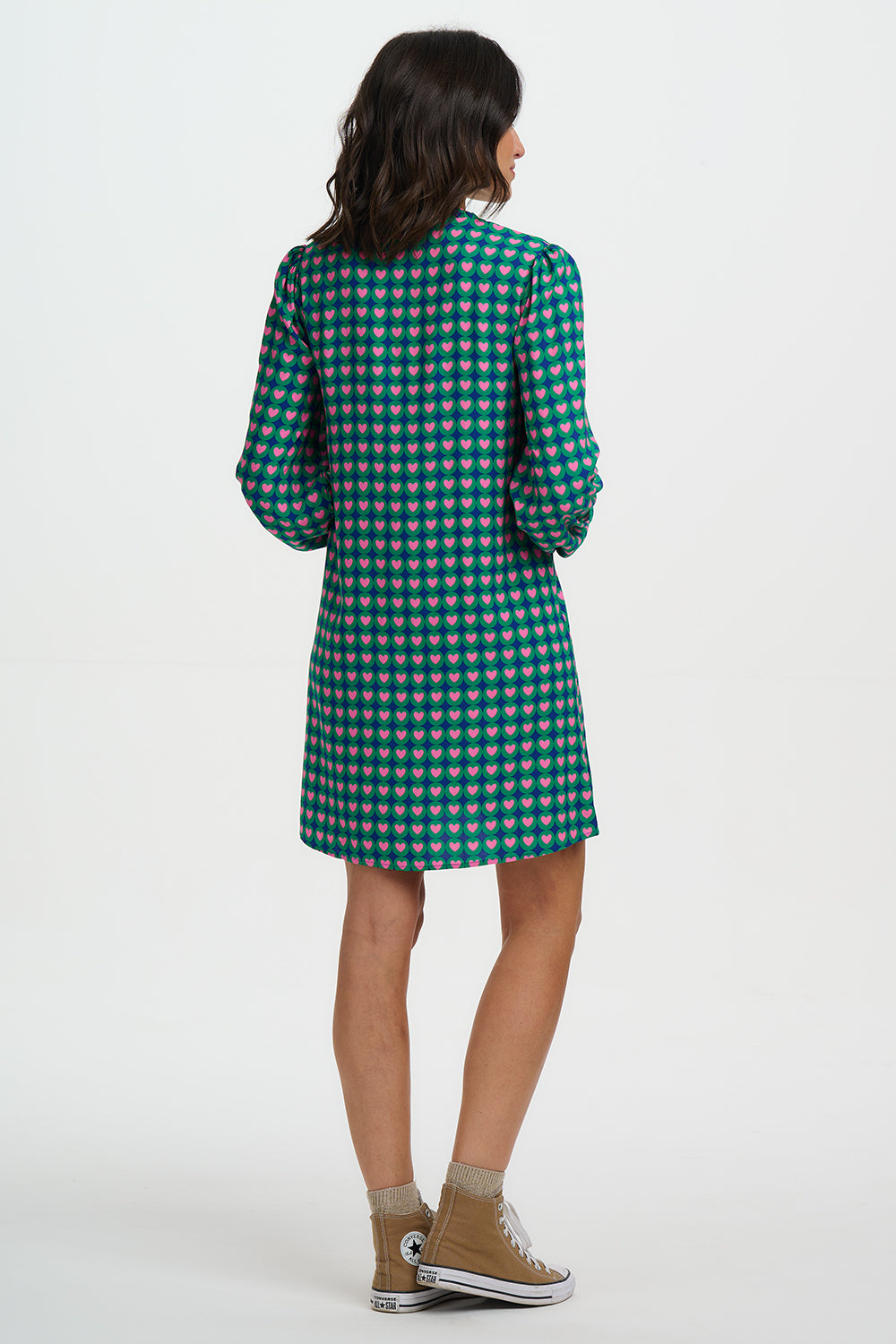 Woman wearing a green checkered dress with beige shoes on a white background