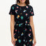 A model wearing a short-sleeved black mini dress with a multicolored hummingbird and garden design, standing against a white background.