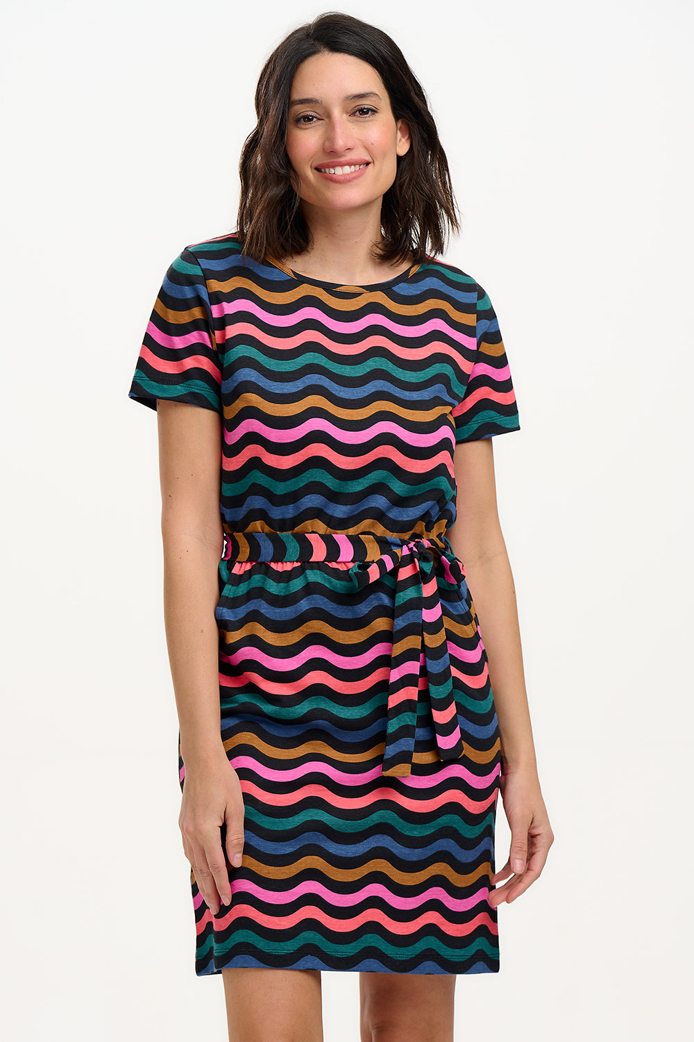 A model wearing a short-sleeved mini dress with a wavy chevron stripe pattern in black, teal, navy, tan, pink, and coral colors.